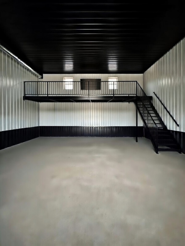 Diamond Garage Condo interior: open main floor, black-and-white corrugated walls, black ceiling, mezzanine and stair